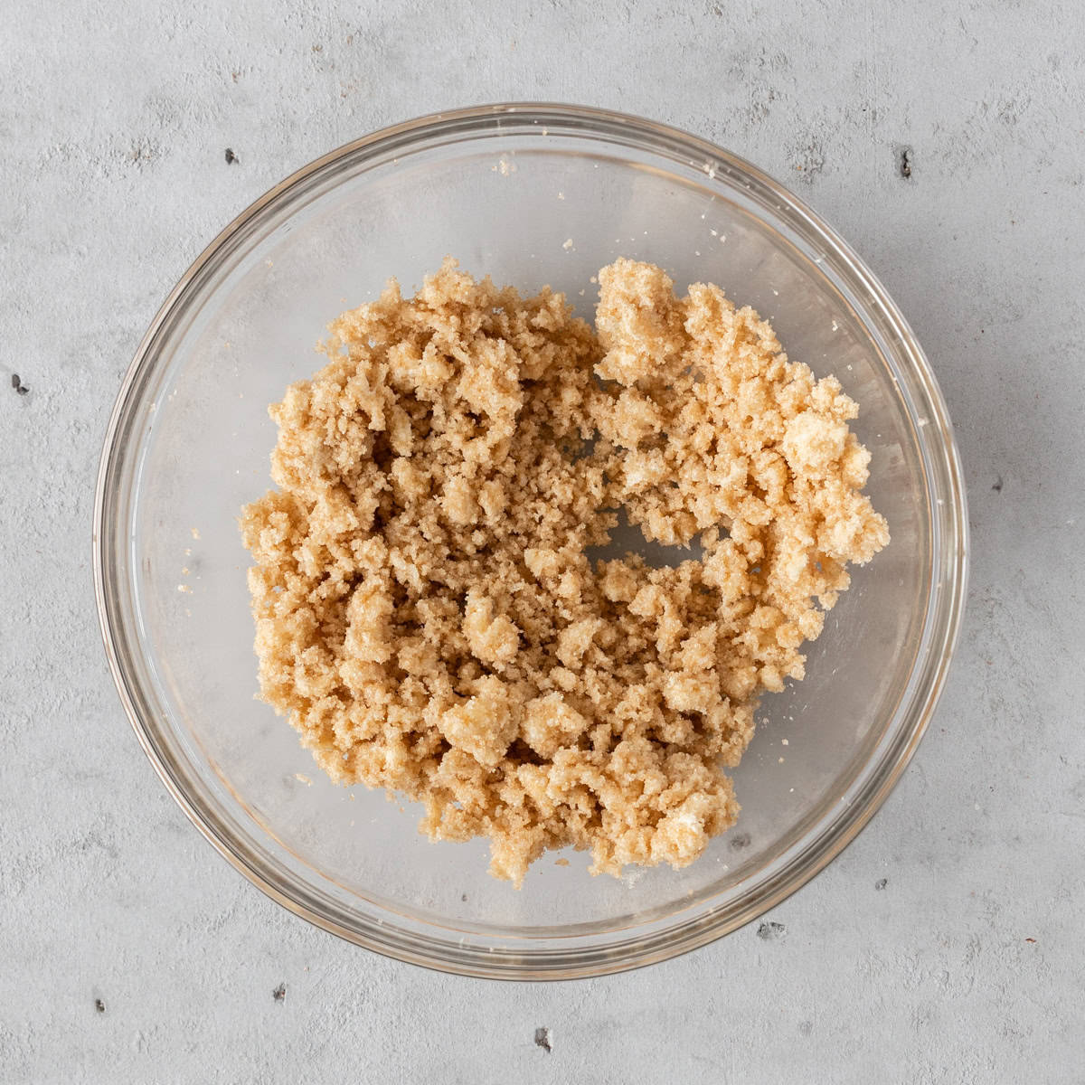 the sugar and butter combined in a glass bowl on a grey background.