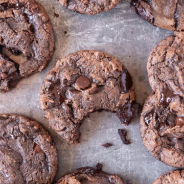 a brownie mix cookie with a bite out of it on a metal baking dish with other cookies around it.