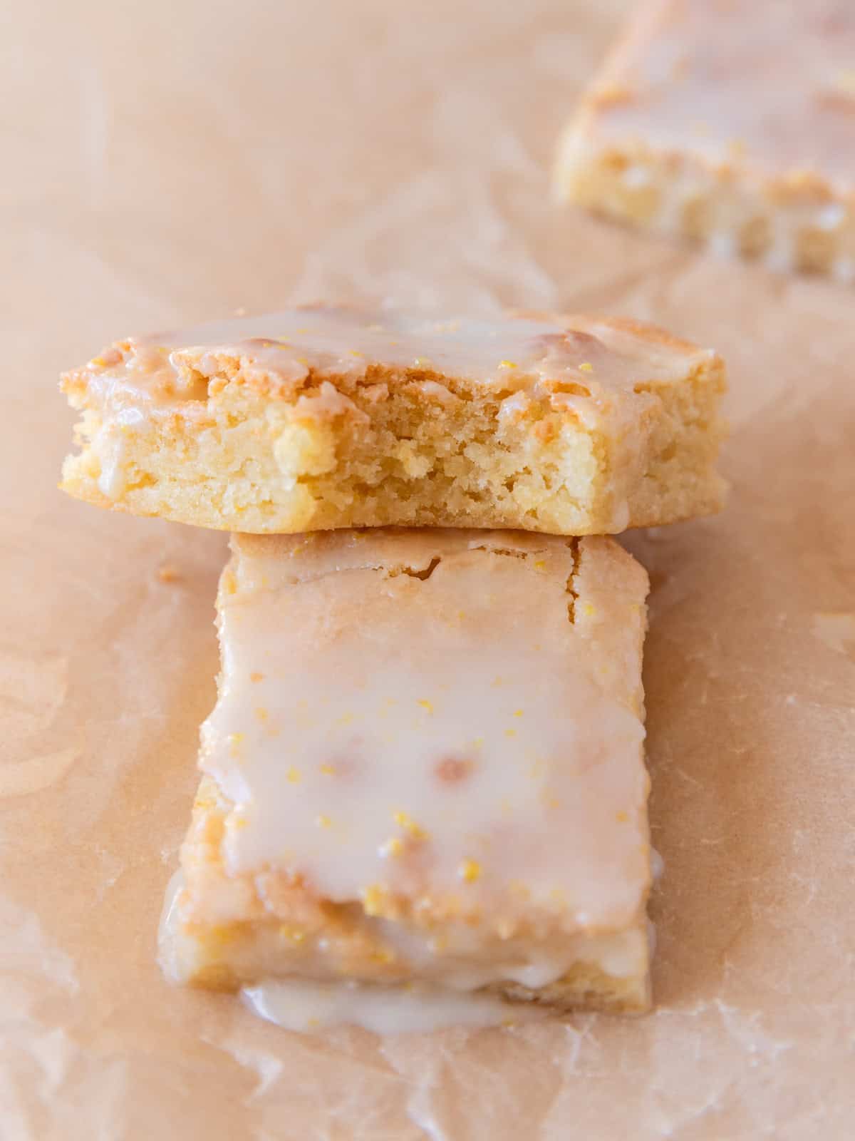 a lemon brownie with a bite out of it propped on top of another lemon brownie.