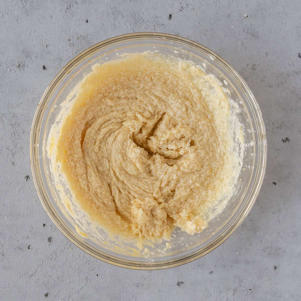 the wet ingredients and sugar combined in a glass bowl on a grey background.