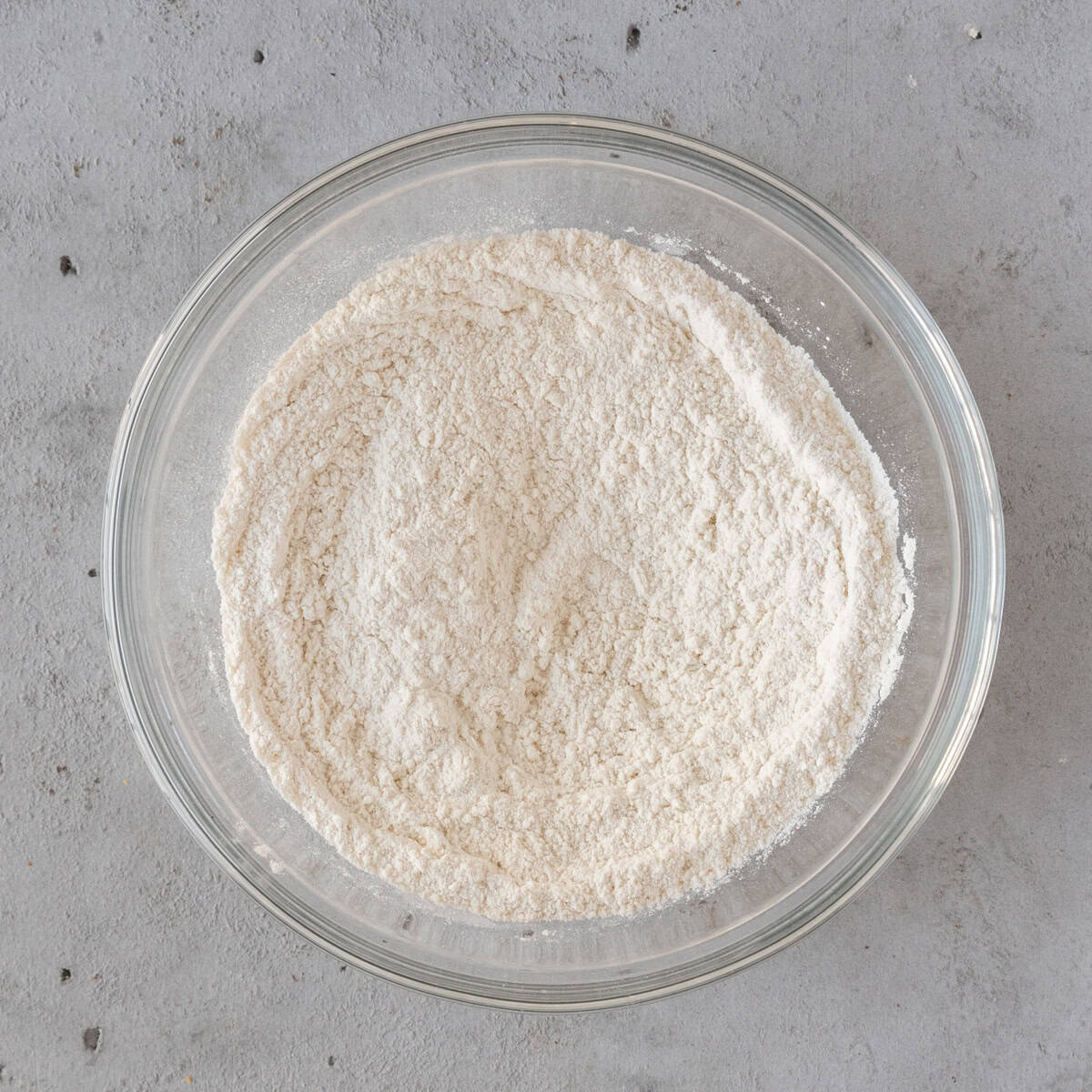 the dry ingredients combined in a glass bowl on a grey background.