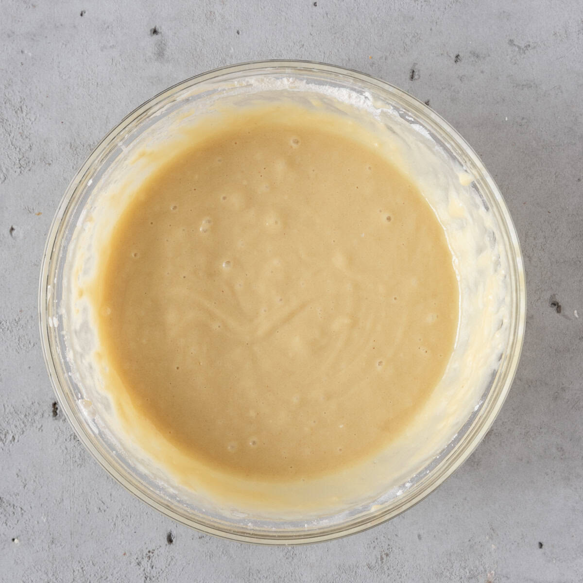 the wet and dry ingredients combined in a glass bowl on a grey background.