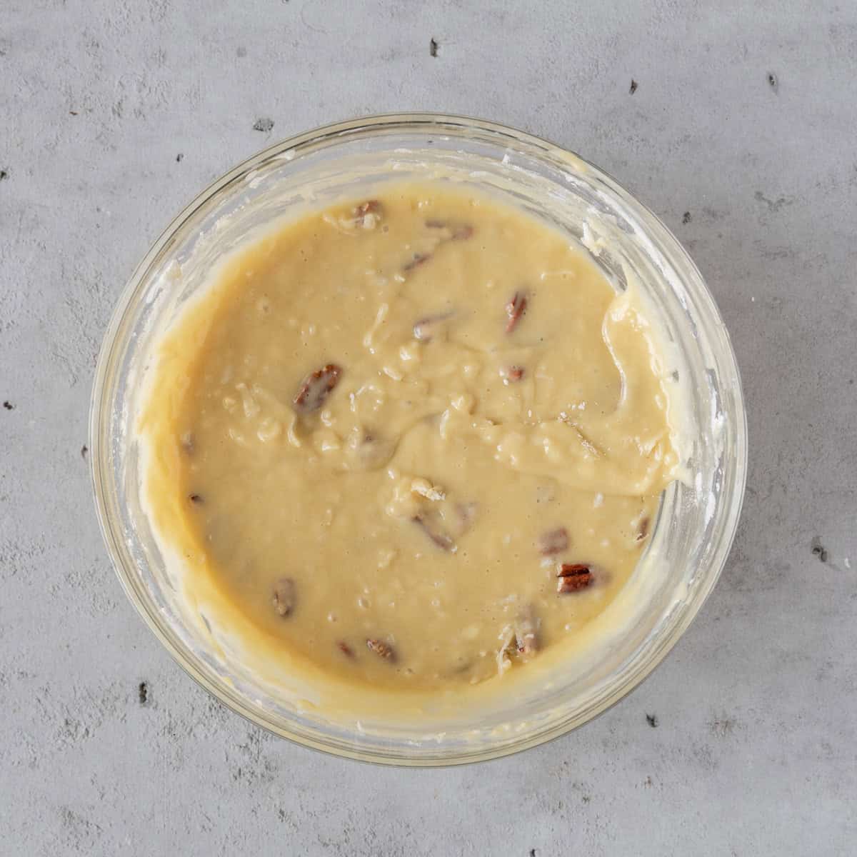 the completed cake batter in a glass bowl on a grey background.