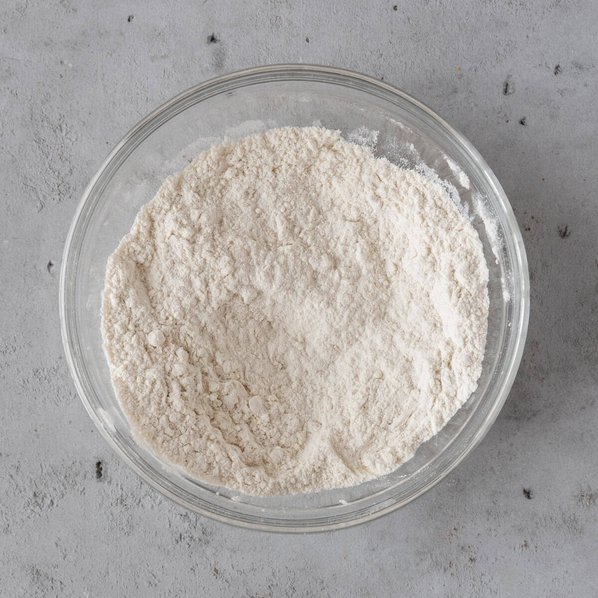 the dry ingredients combined in a glass bowl on a grey background.