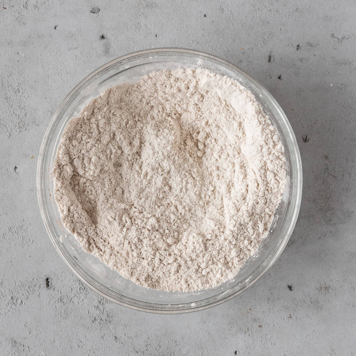 the dry ingredients combined in a glass bowl on a grey background.