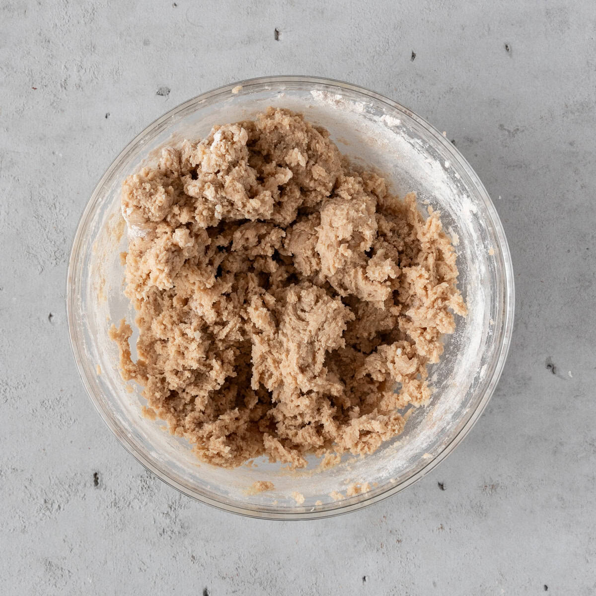 the completed cookie dough in a glass bowl on a grey background.