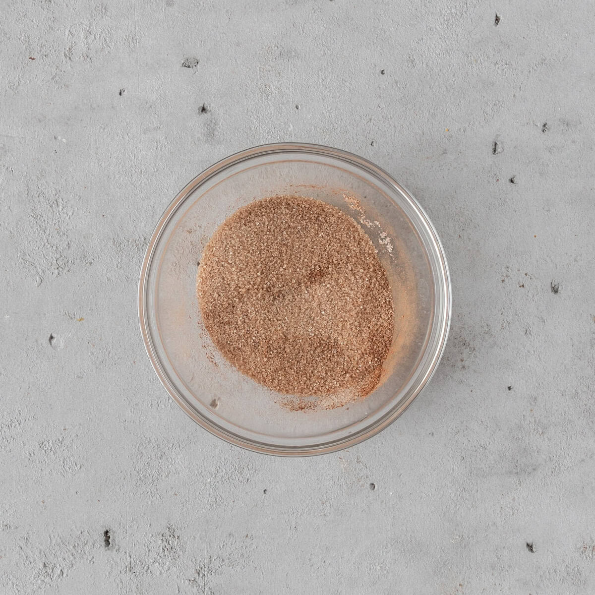 the cinnamon and sugar combined in a glass bowl on a grey background.
