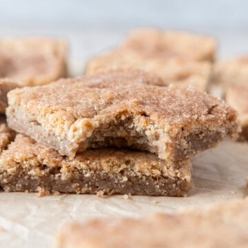 a snickerdoodle cookie bar with a bite out of it on top of another cookie bar.