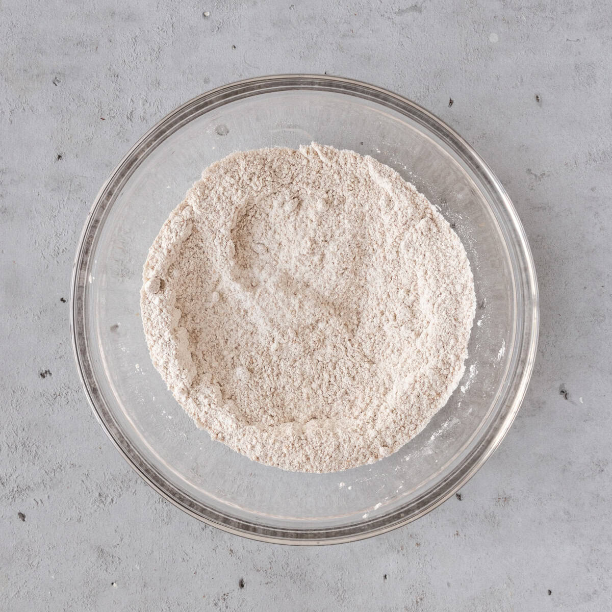 the dry ingredients combined in a glass bowl on a grey background.
