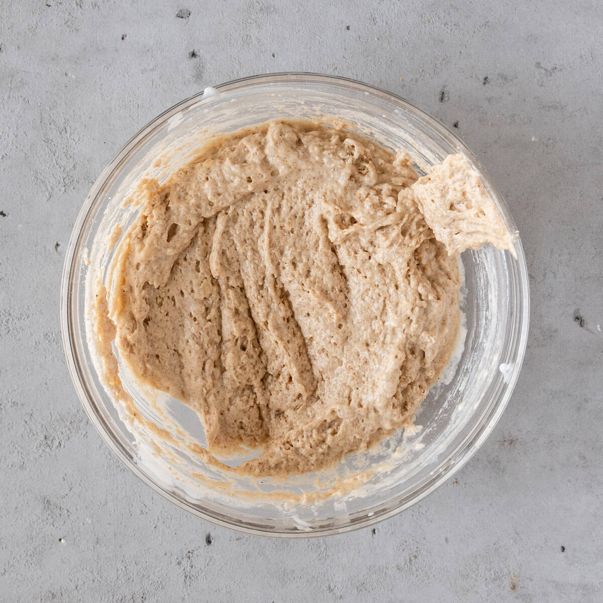 the completed muffin batter in a glass bowl on a grey background.