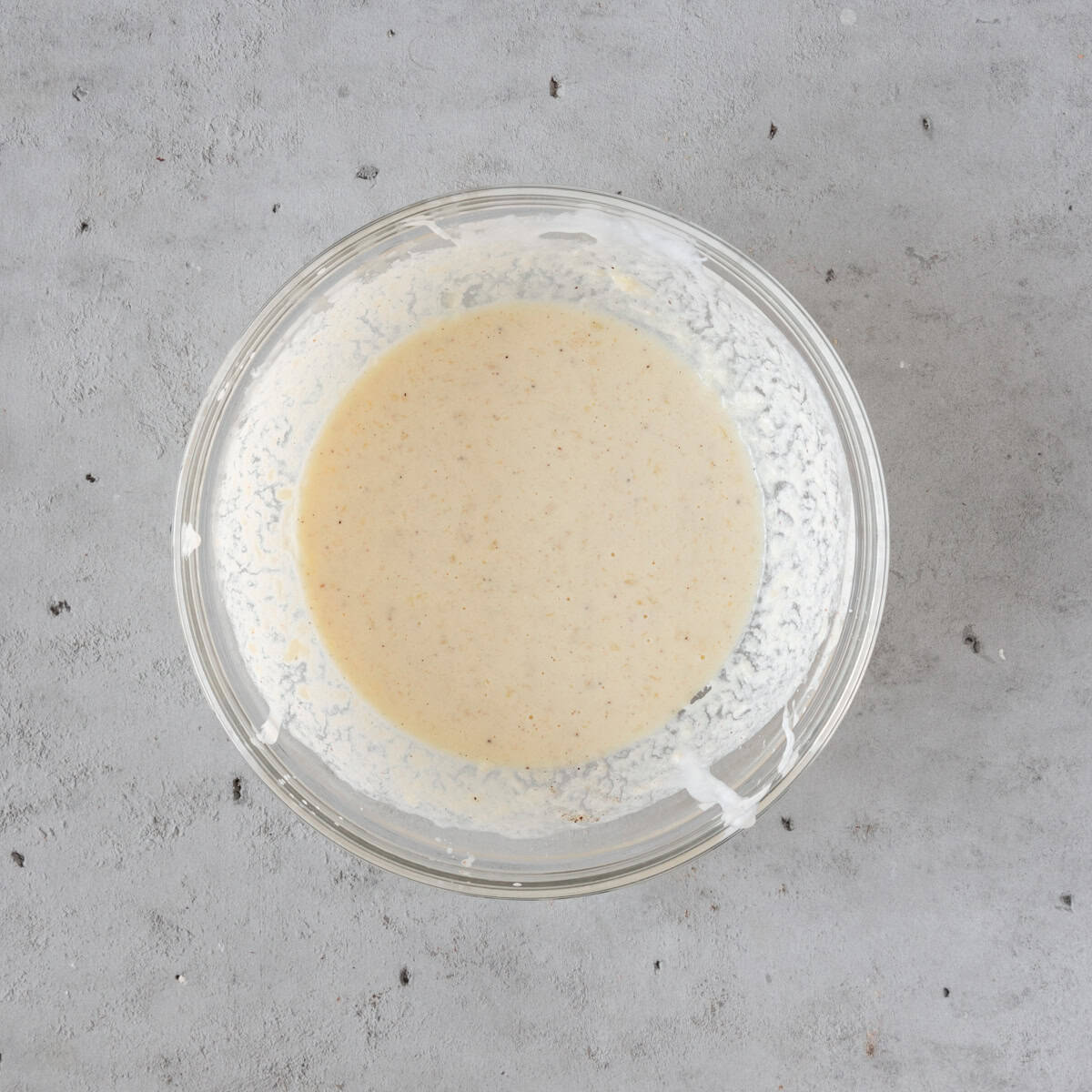 the wet ingredients combined in a glass bowl on a grey background.