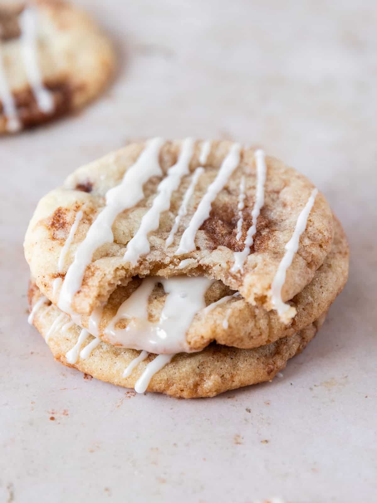 three cinnamon roll cookies stacked on top of each other. One has a bite out of it.