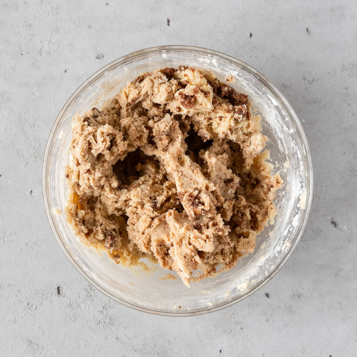 the cinnamon roll filling combined with the cookie dough in a glass bowl on a grey background.