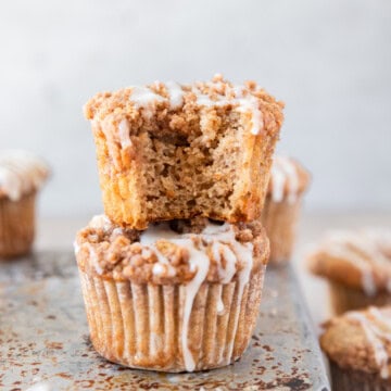 two coffee cake muffins stacked on top of each other. One has a bite out of it.