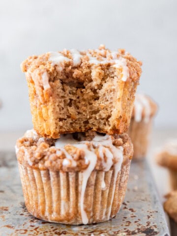 two coffee cake muffins stacked on top of each other. One has a bite out of it.