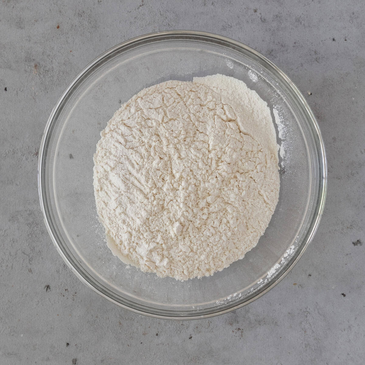 the dry ingredients combined in a glass bowl on a grey background.