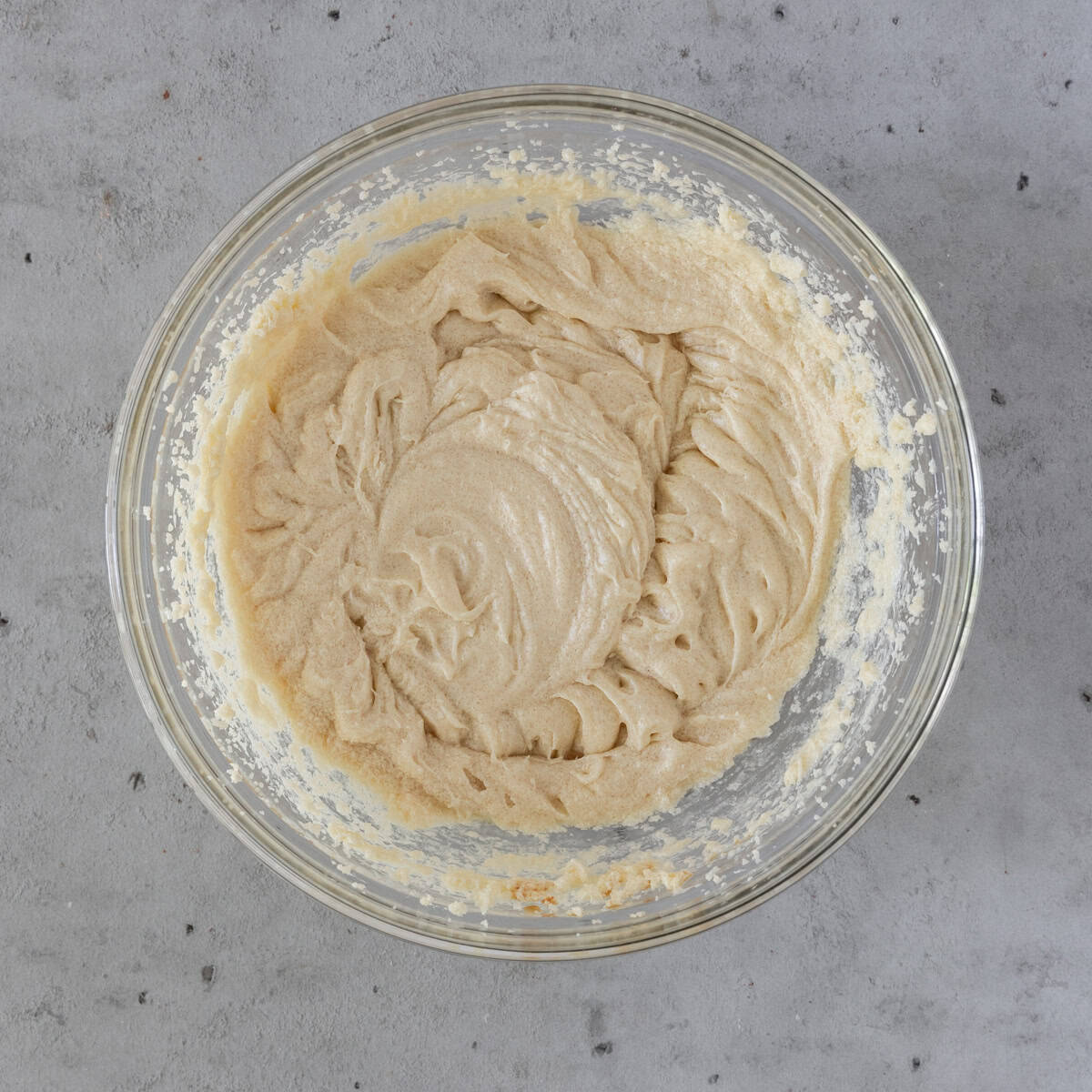 the wet ingredients and sugar combined in a glass bowl on a grey background.