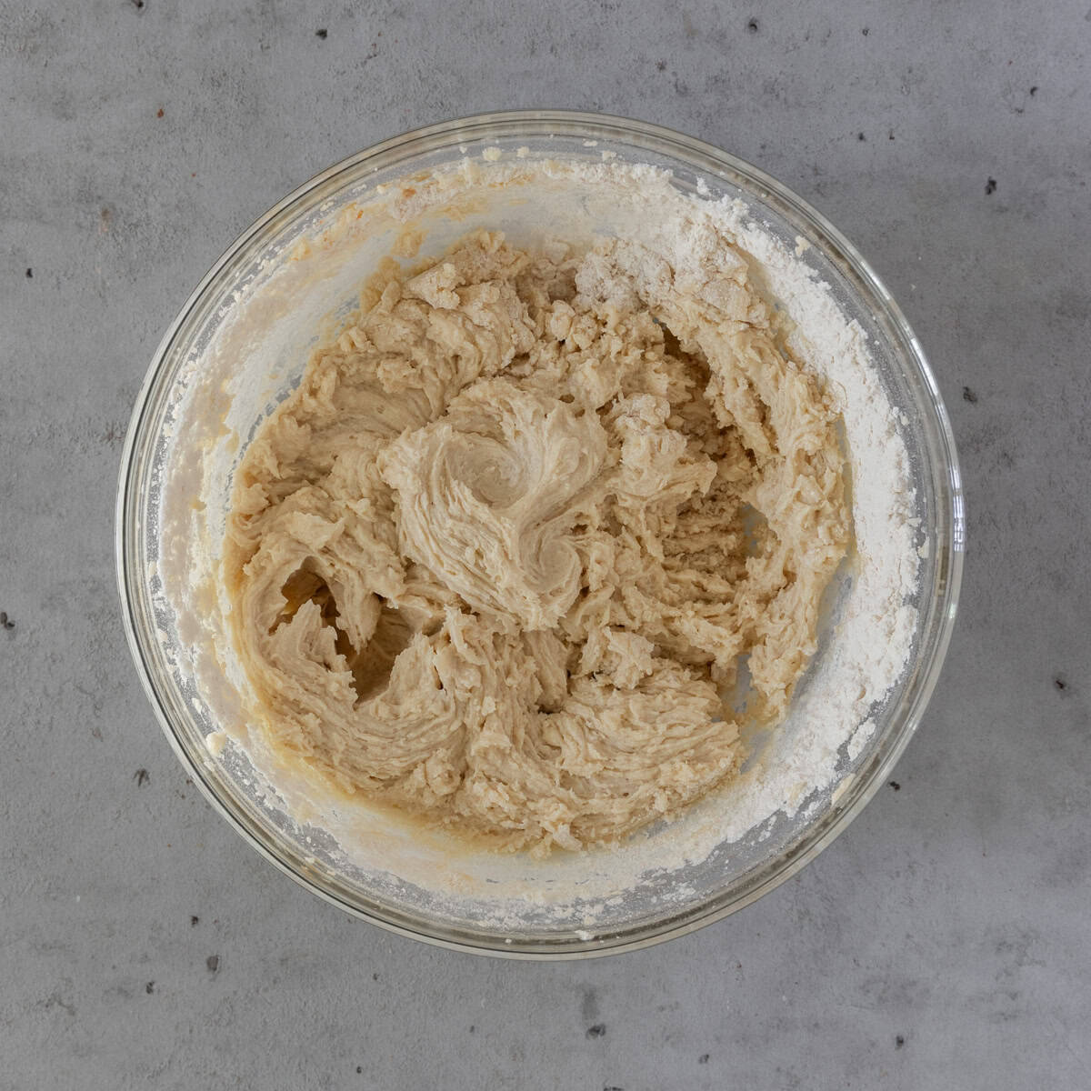the wet and dry ingredients combined in a glass bowl on a grey background.