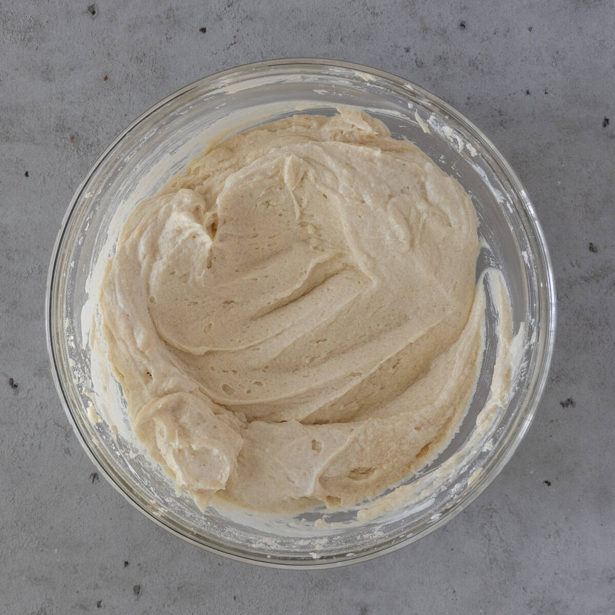 the completed vanilla cake batter in a glass bowl on a grey background.