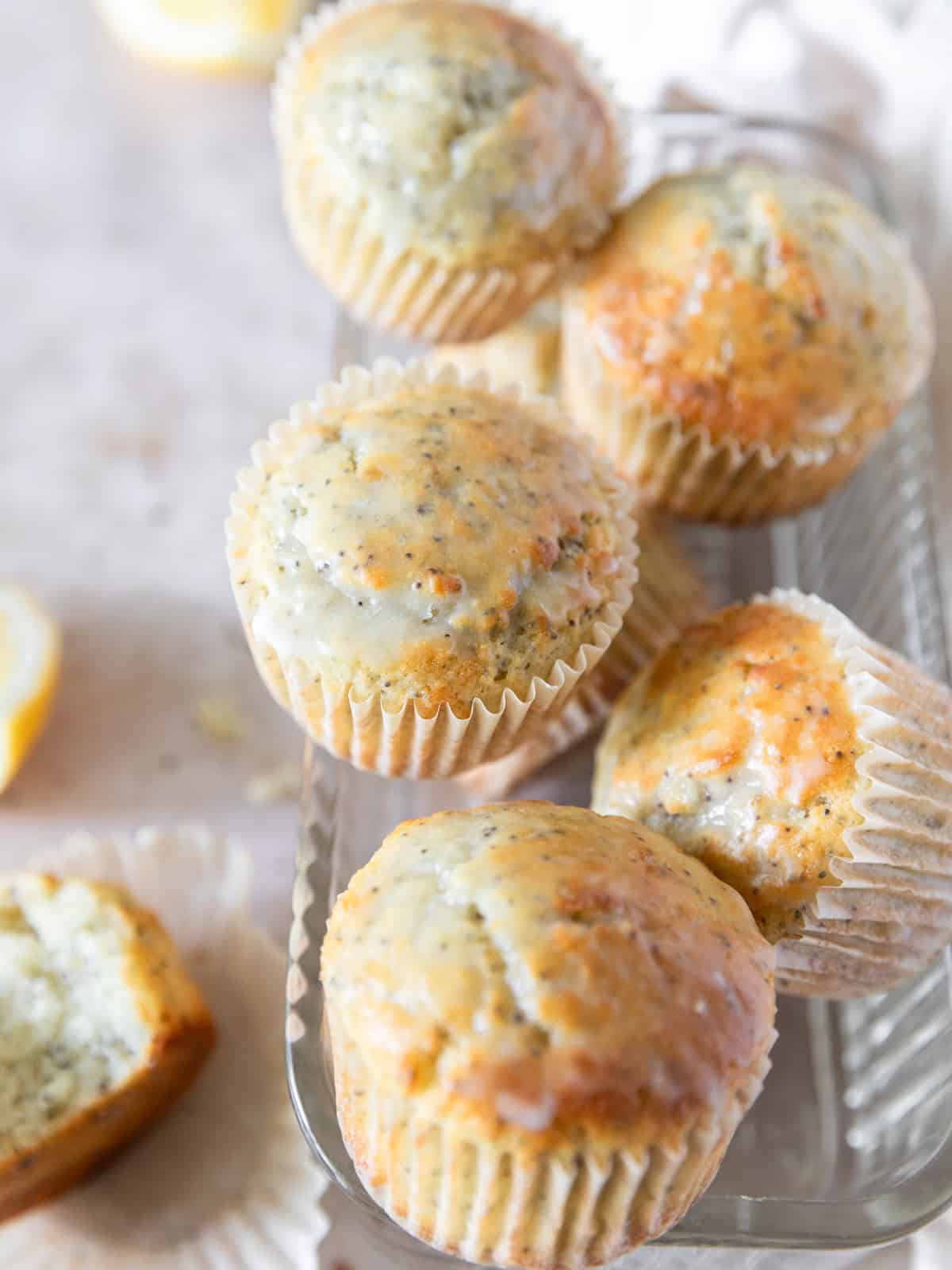 several lemon poppy seed muffins stacked in a glass container.