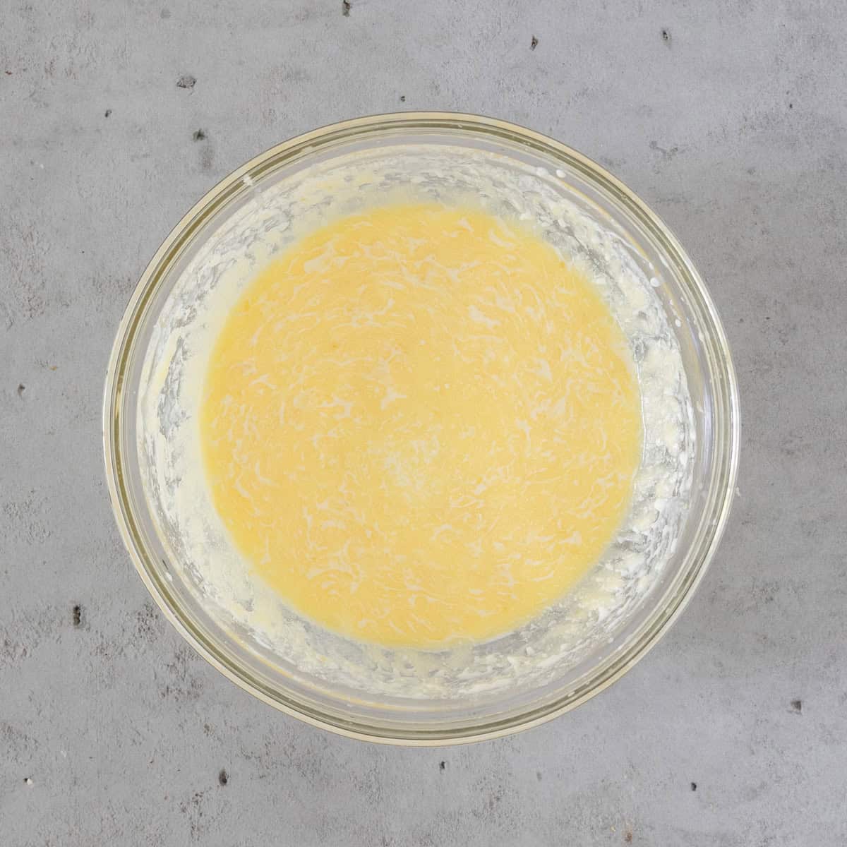 the wet ingredients combined in a glass bowl on a grey background.