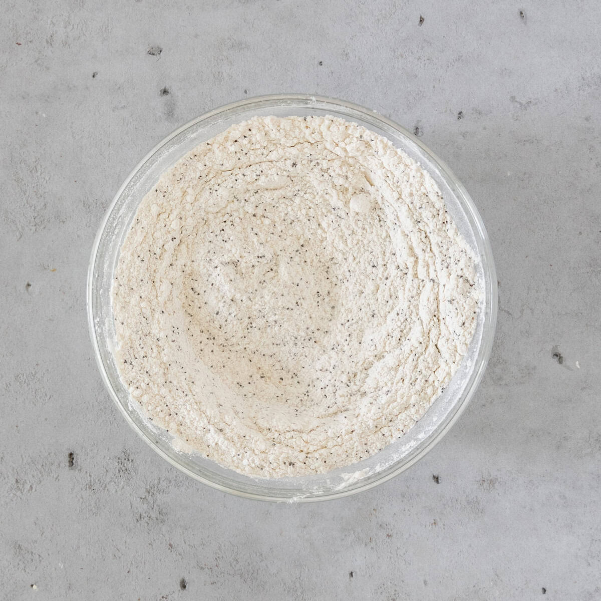 the dry ingredients combined in a glass bowl on a grey background.