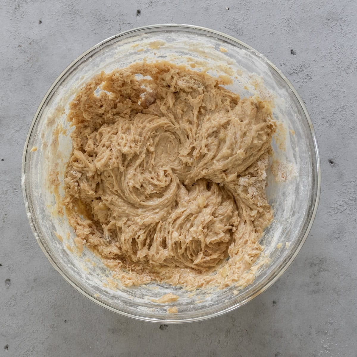 the wet and dry ingredients combined in a glass bowl on a grey background.