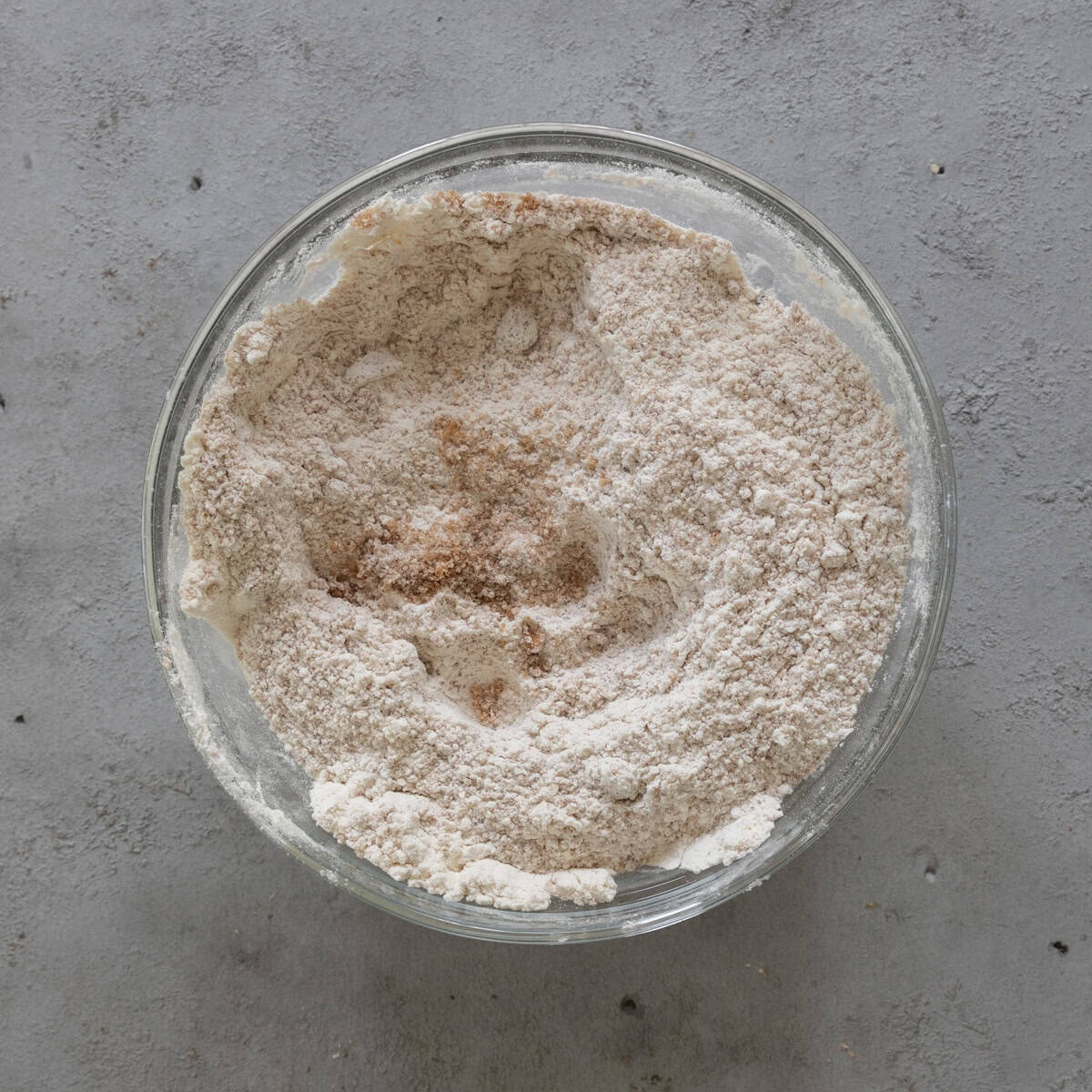 the dry ingredients combined in a glass bowl on a grey background.