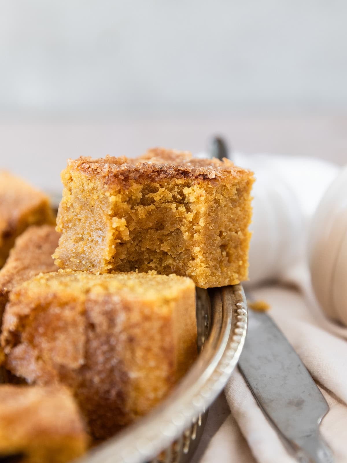 a silver tray of pumpkin blondies. The one on top has a bite out of it.
