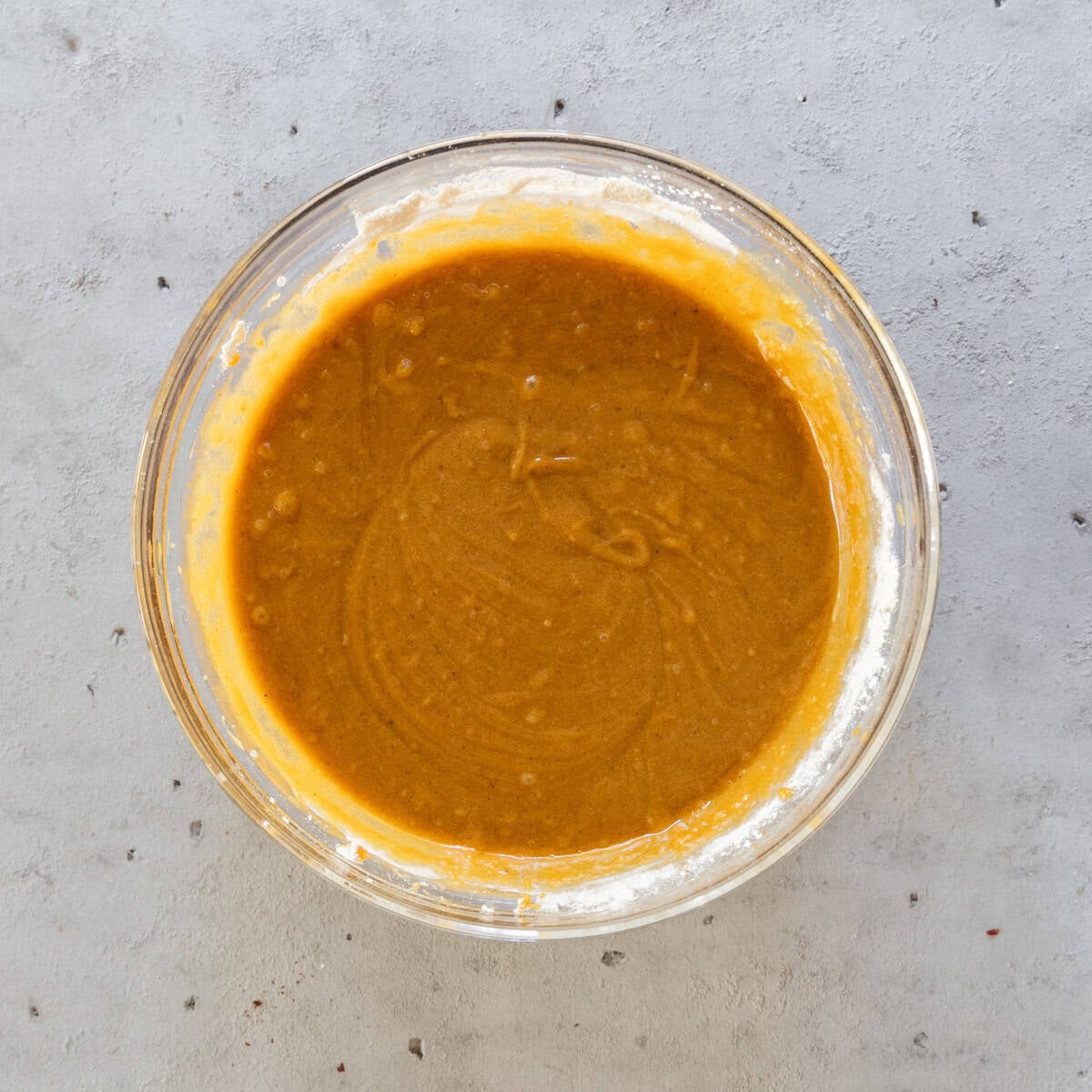 the completed pumpkin blondie batter in a glass bowl on a grey background.