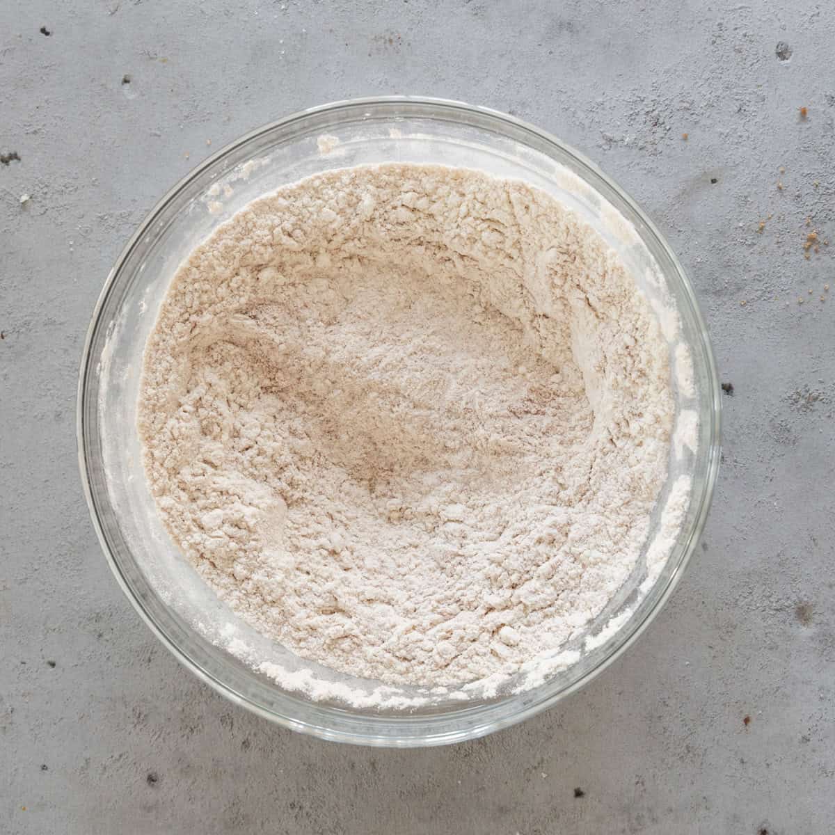 the dry ingredients combined in a glass bowl on a grey background.