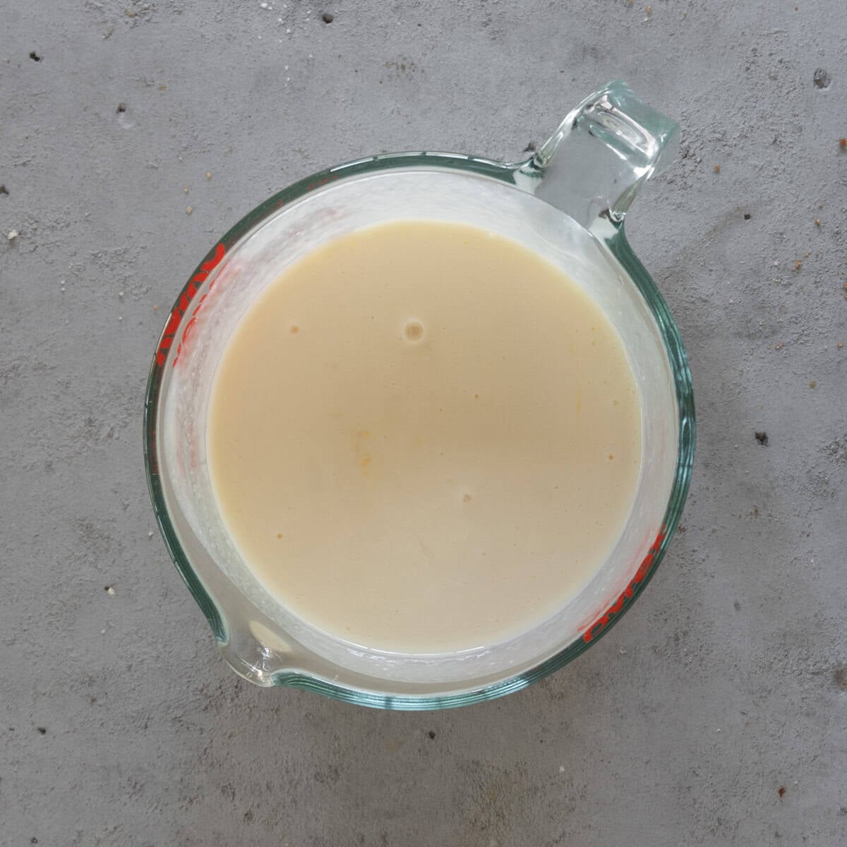the wet ingredients combined in a glass measuring cup on a grey background.