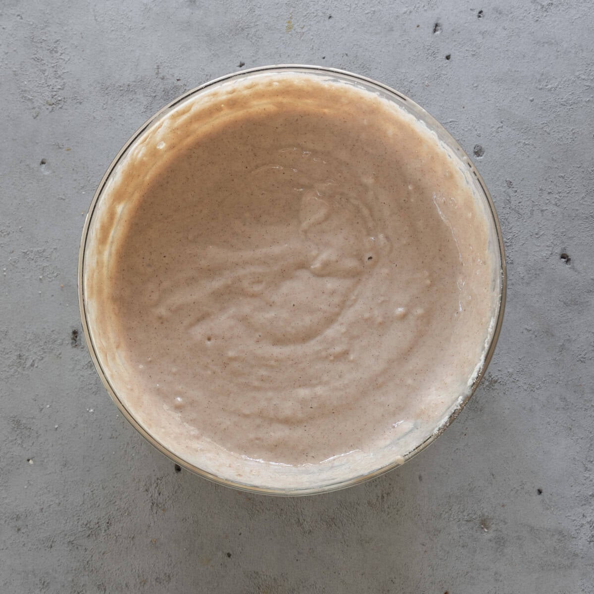 the completed cinnamon pancake batter in a glass bowl on a grey background.