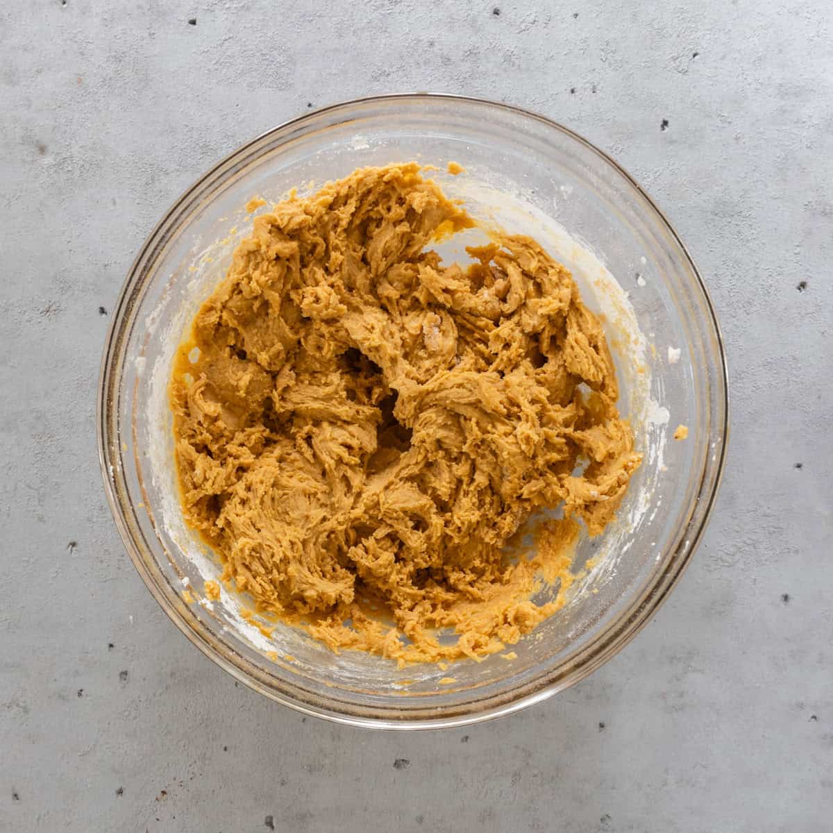 the wet and dry ingredients combined in a glass bowl on a grey background.