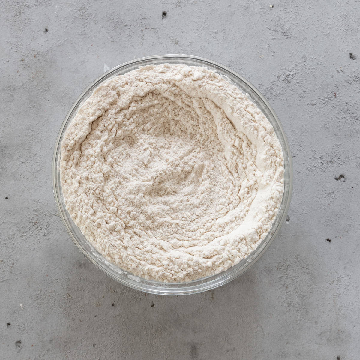 the dry ingredients combined in a glass bowl on a grey background.
