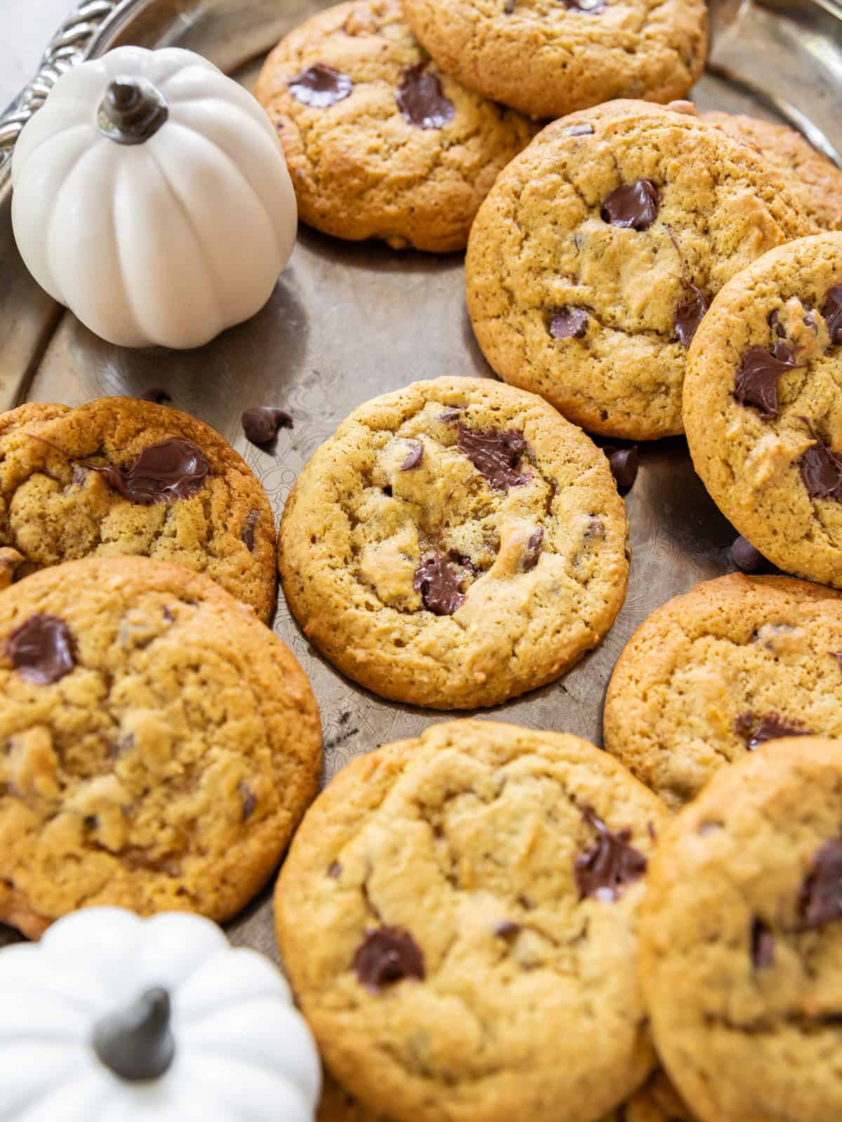 a tray of soft and chewy pumpkin chocolate chip cookies on a silver tray.