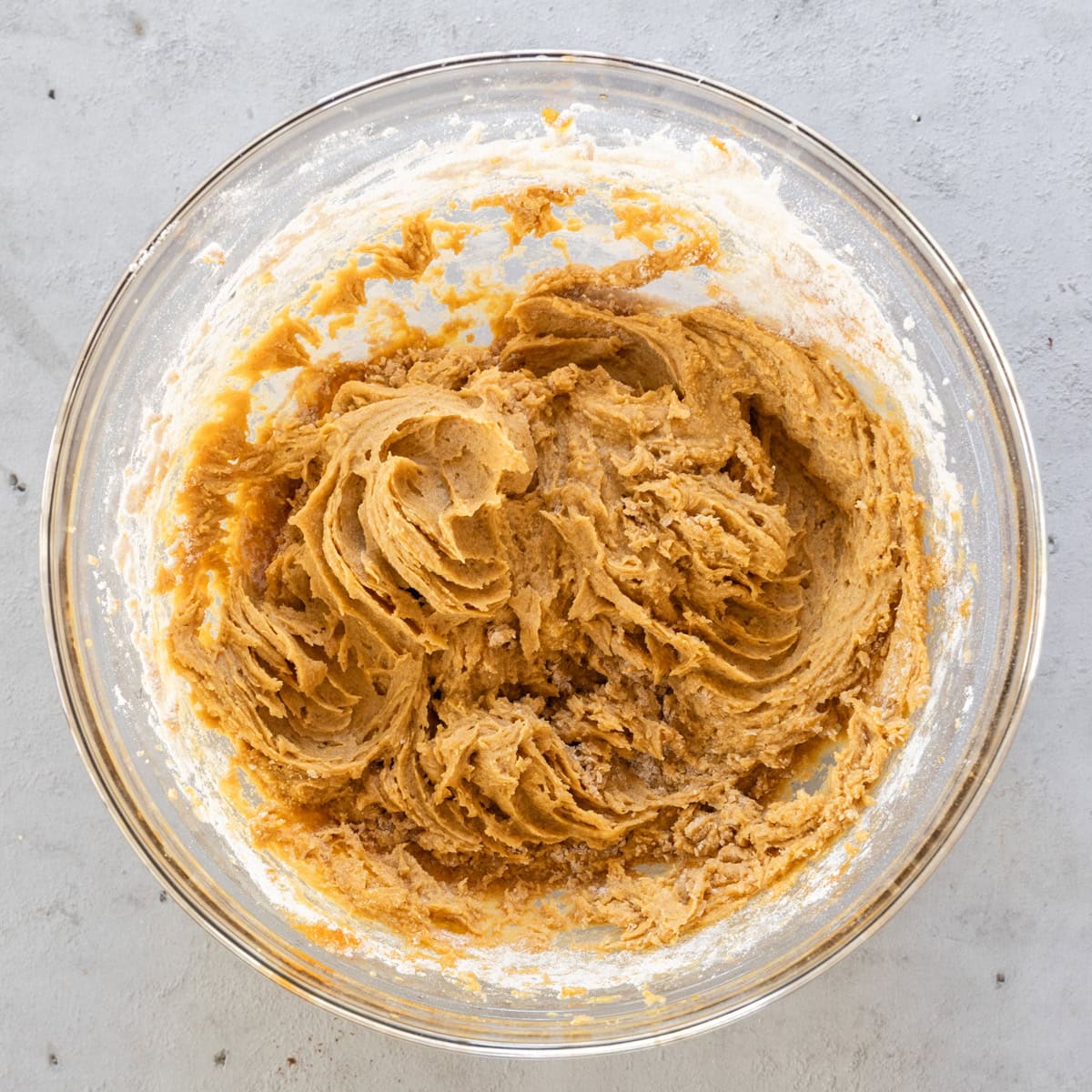 the wet and dry ingredients combined in a glass bowl on a grey background.