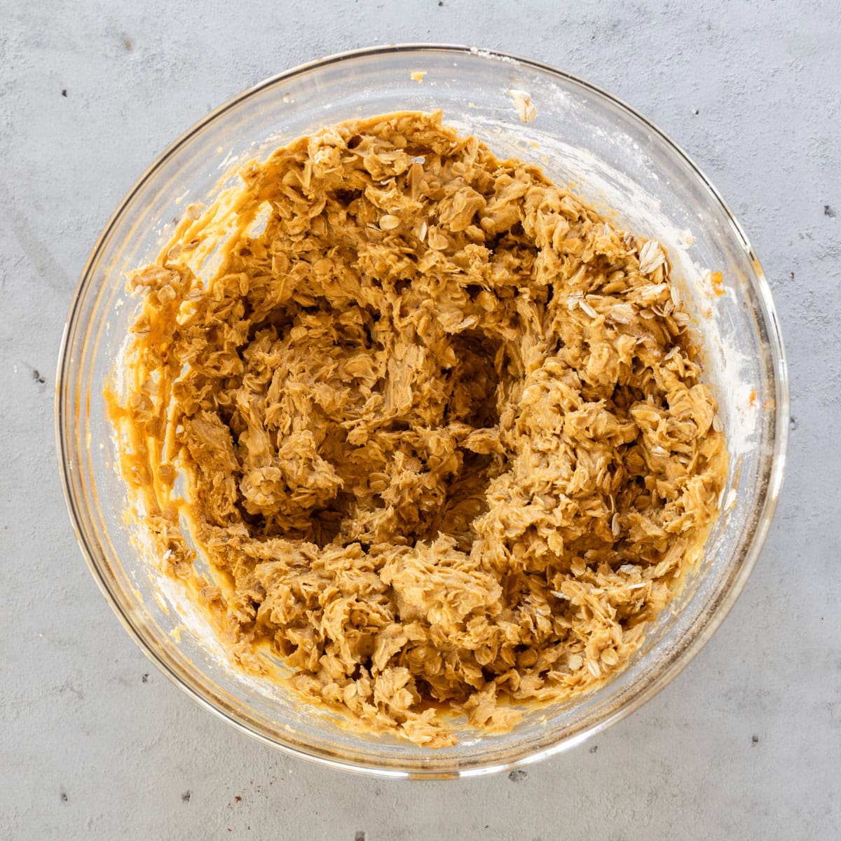the completed pumpkin oatmeal cookie dough in a glass bowl on a grey background.