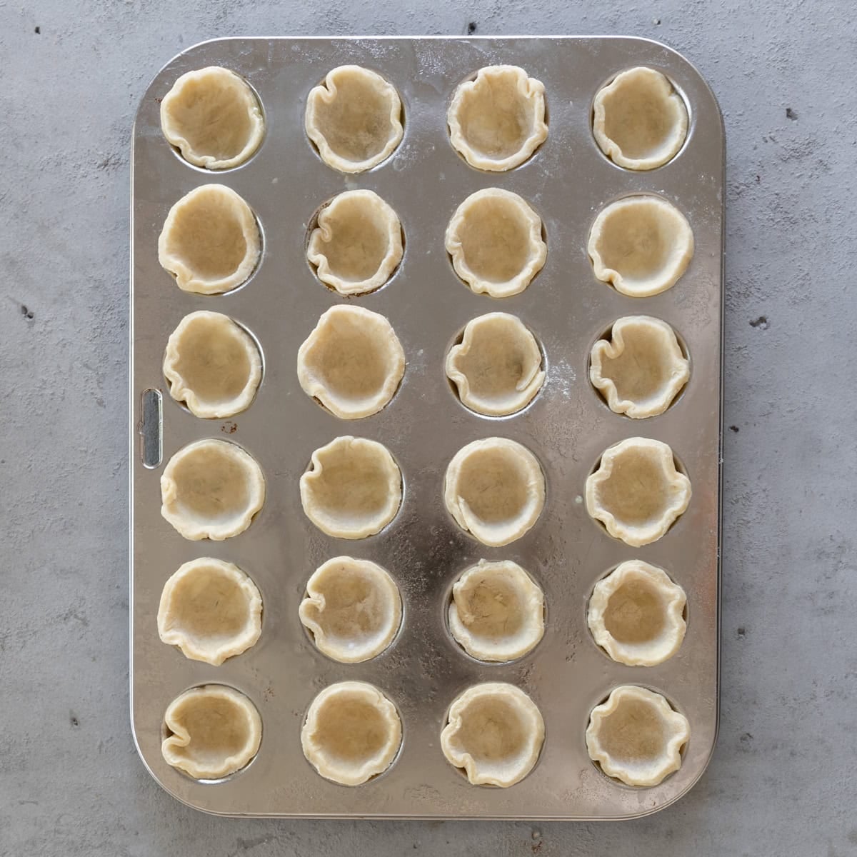 the pie dough in the mini muffin tin before being filled.