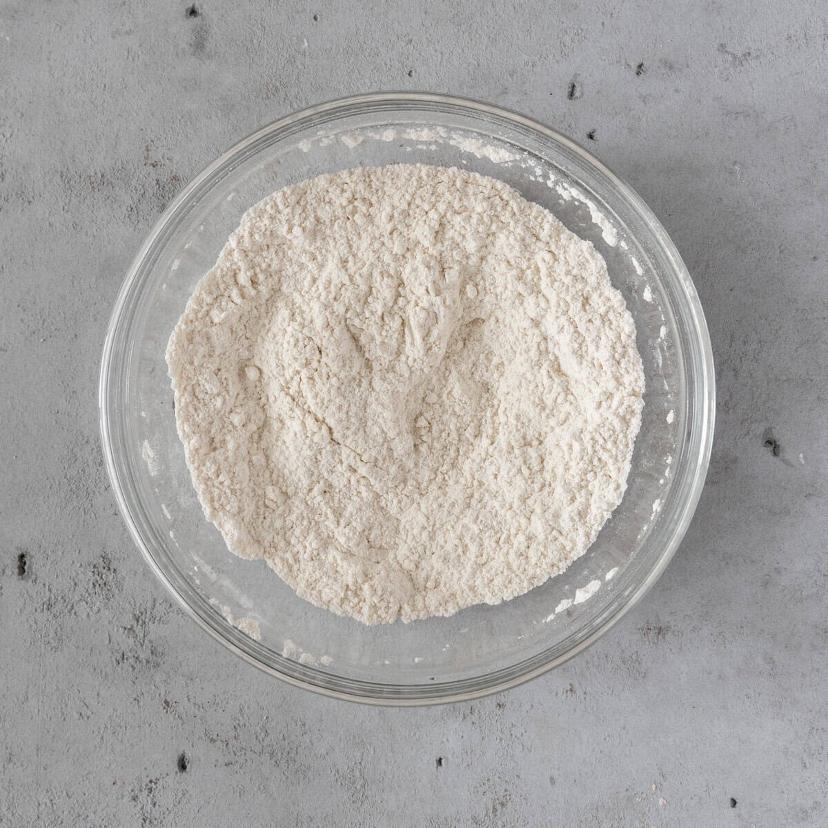 the dry ingredients combined in a glass bowl on a grey background.