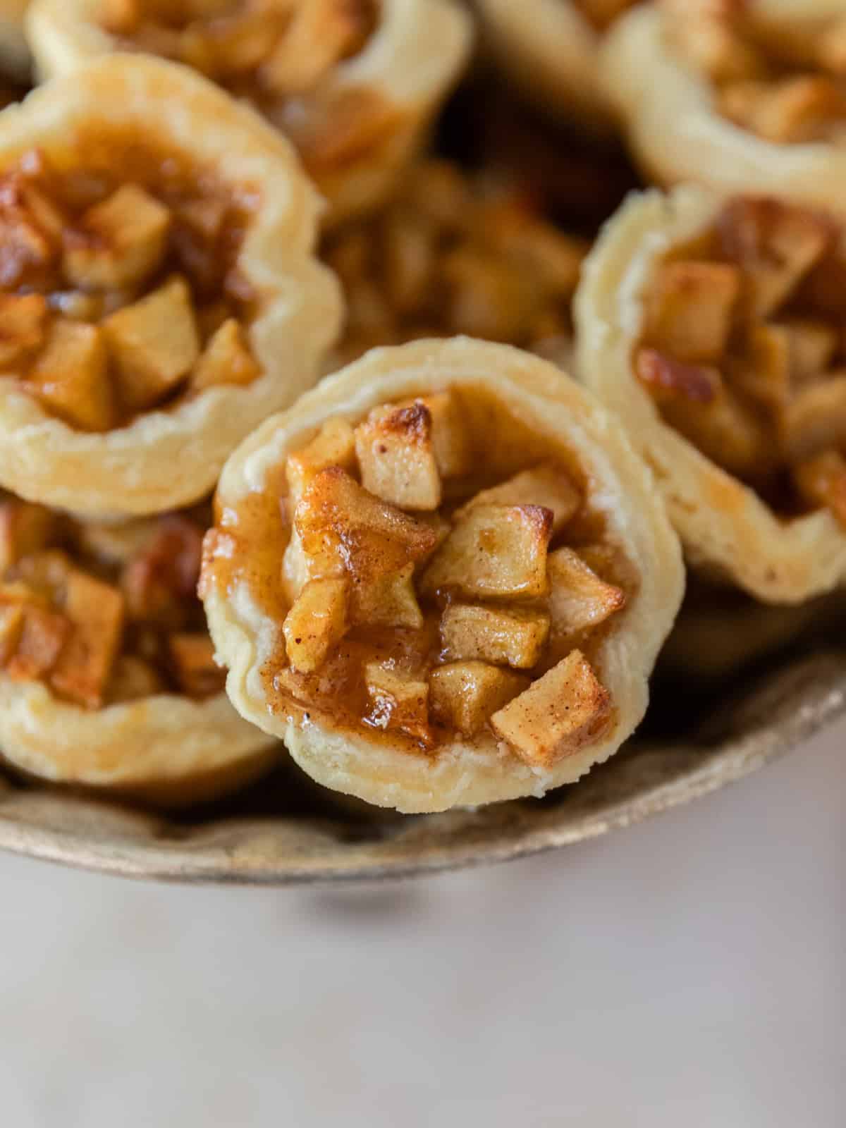 several mini apple pies in a silver dish.