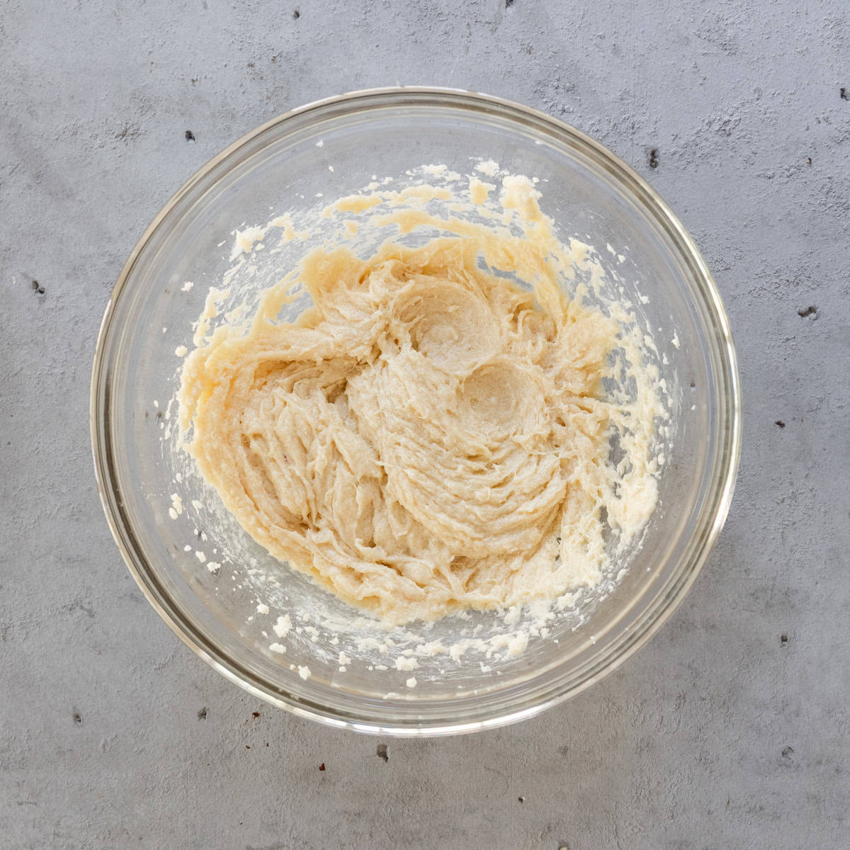 the wet ingredients and sugar combined in a glass bowl on a grey background.