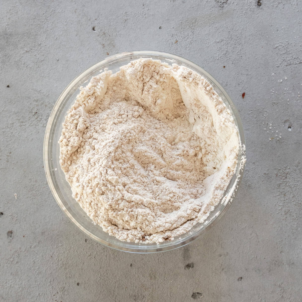 the dry ingredients combined in a glass bowl on a grey background.