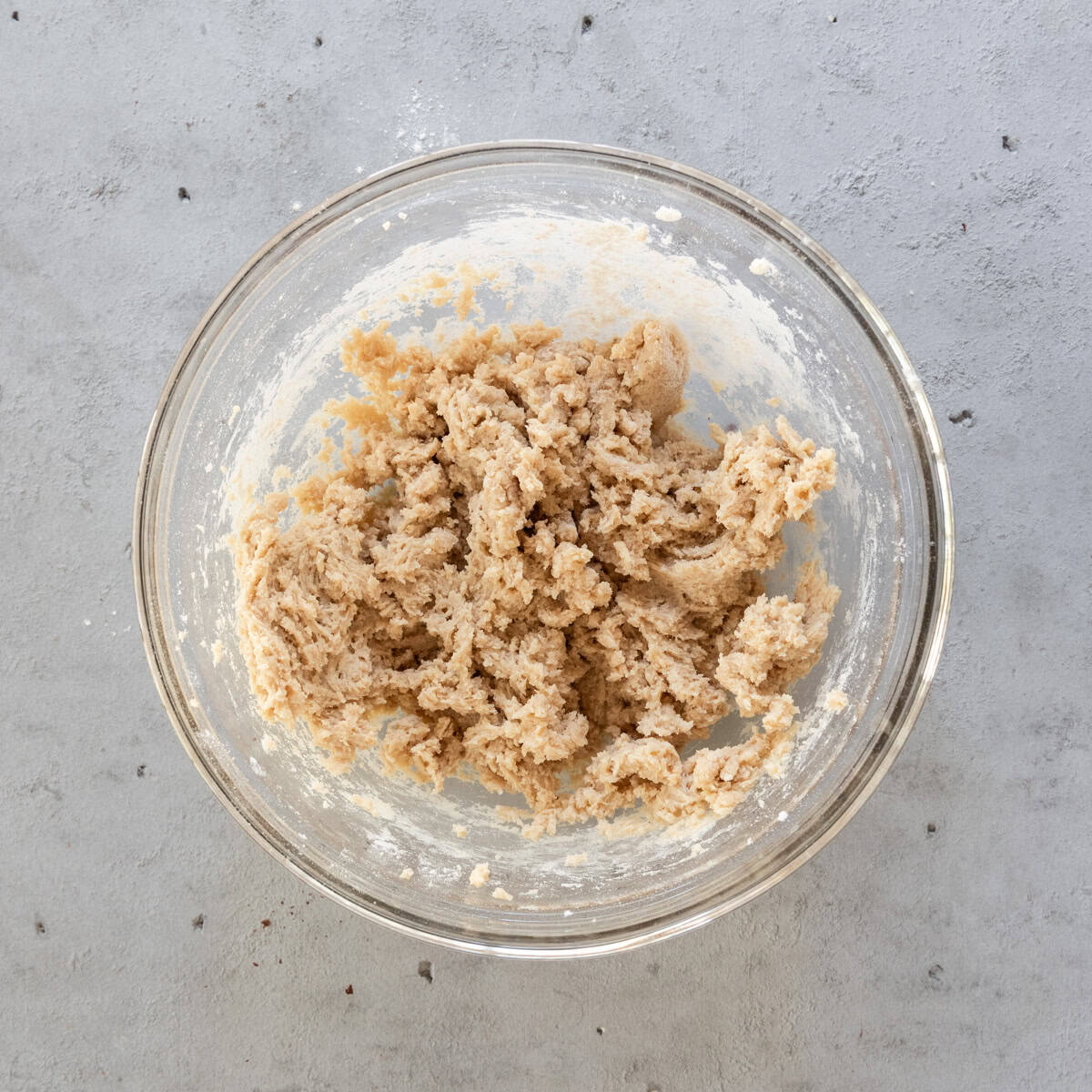 the wet and dry ingredients combined in a glass bowl on a grey background.