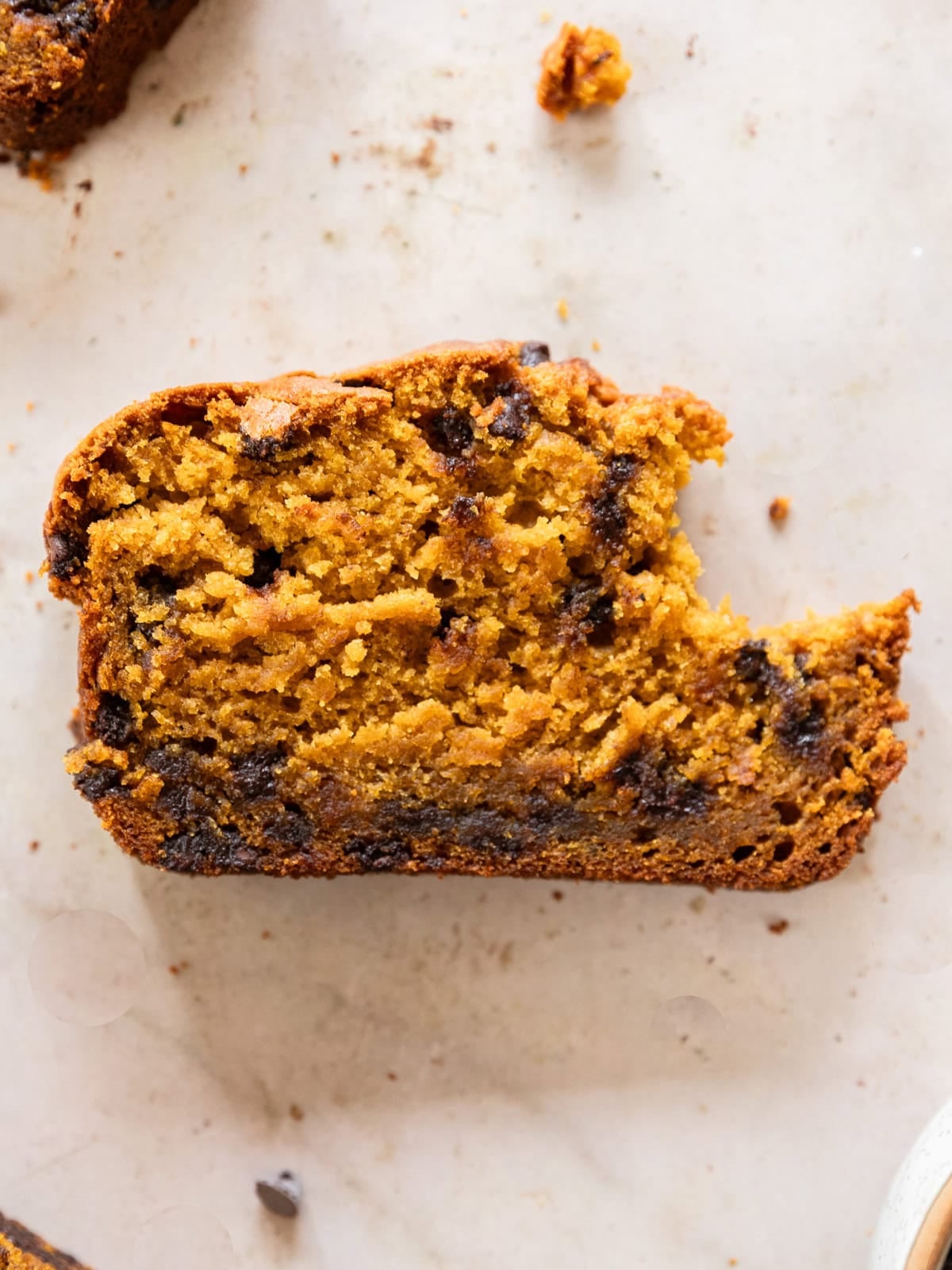 a slice of small batch pumpkin chocolate chip bread with a bite taken out of it.