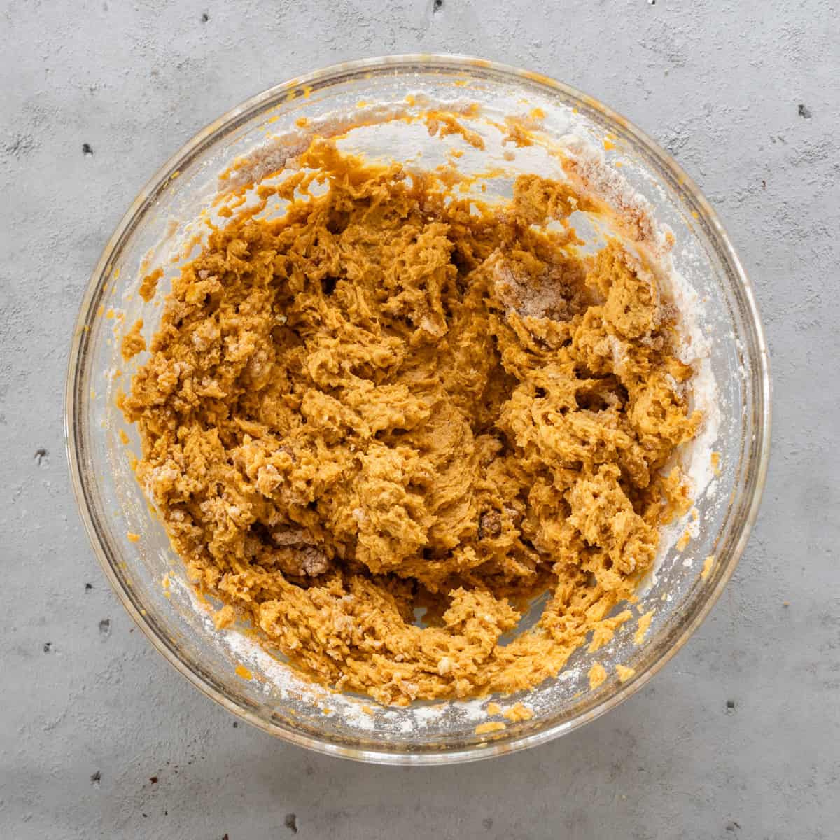 the wet and dry ingredients combined in a glass bowl on a grey background.