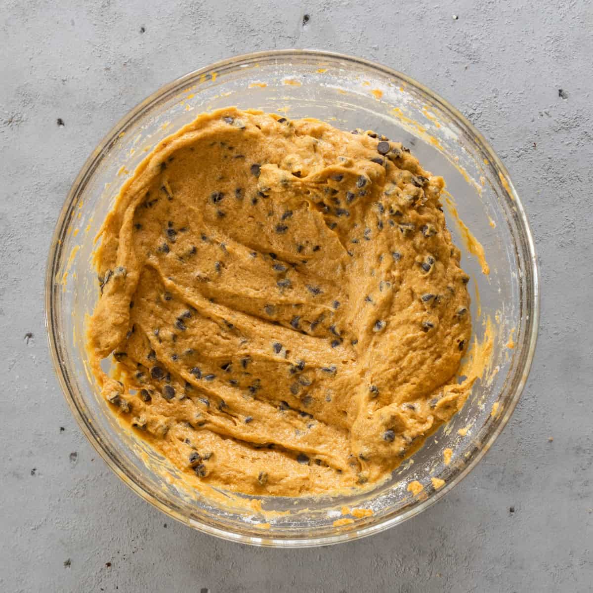 the completed pumpkin chocolate chip bread batter in a glass bowl on a grey background.