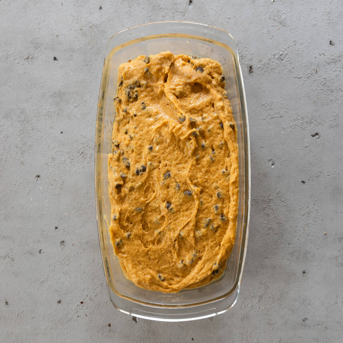 the pumpkin chocolate chip bread in a glass bread dish before being baked.
