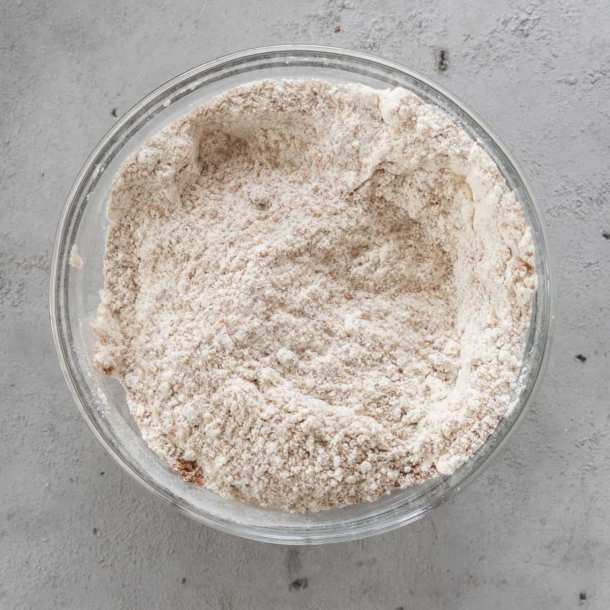 the dry ingredients combined in a glass bowl on a grey background.