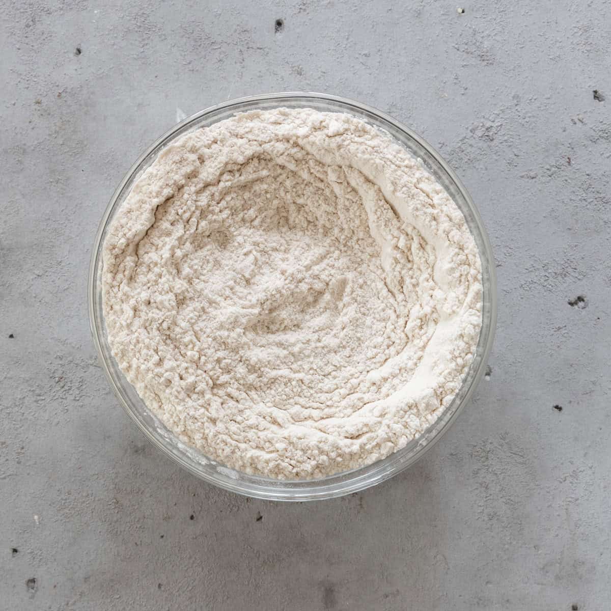 the dry ingredients combined in a glass bowl on a grey background.